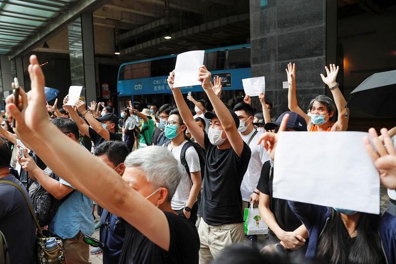 Hong Kongers raising sheets of white paper devoid of slogans banned under the national security law as they supported an arrested protester outside a court in the city yesterday. The law punishes crimes of secession, subversion, terrorism and collusi