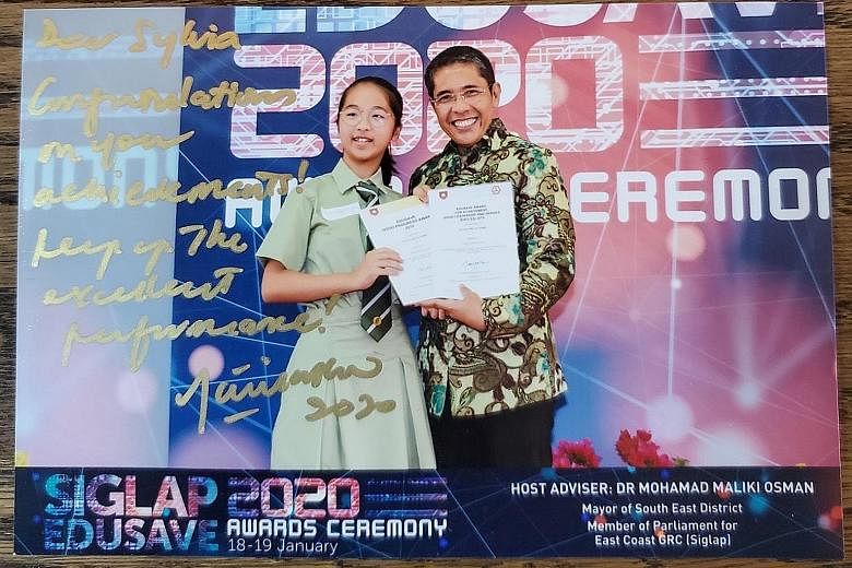 Secondary 1 student Sylvia Low receiving the Edusave Merit Bursary and Edusave Good Progress Award in January from Dr Maliki Osman, Mayor of South East District. Dr Maliki linked her up with families who needed help. PHOTO: JEFF LOW