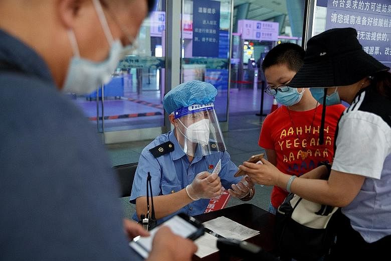 An employee checking the identity and health status of travellers before they enter the Beijing South Railway Station on Friday. PHOTO: REUTERS