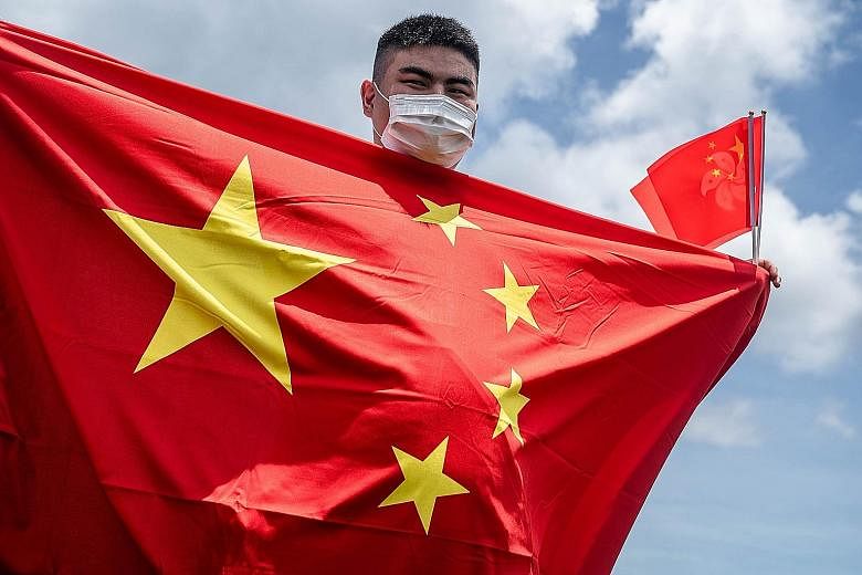 A Chinese government supporter holding the flags of China and Hong Kong to mark the passing of the new national security law. PHOTO: BLOOMBERG