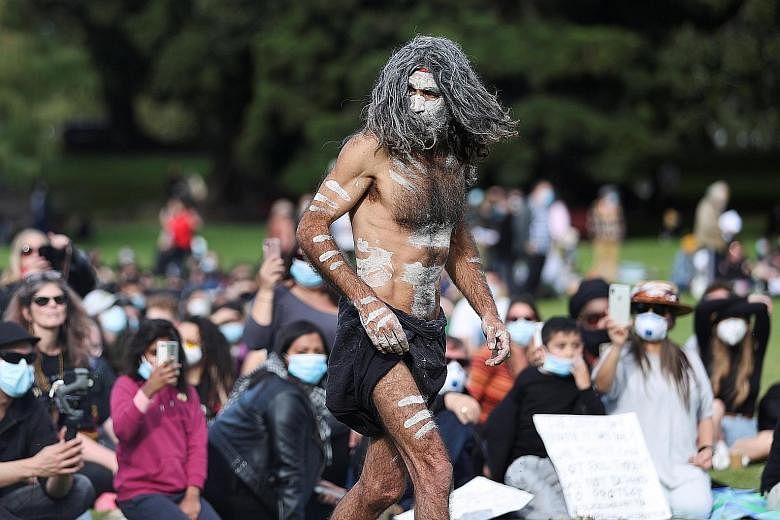 Above: A Black Lives Matter rally in Sydney yesterday, which also called for increased focus on the mistreatment of indigenous people. Left: An Aboriginal elder taking part in an ancient smoking ceremony, which was attended by families of those who h