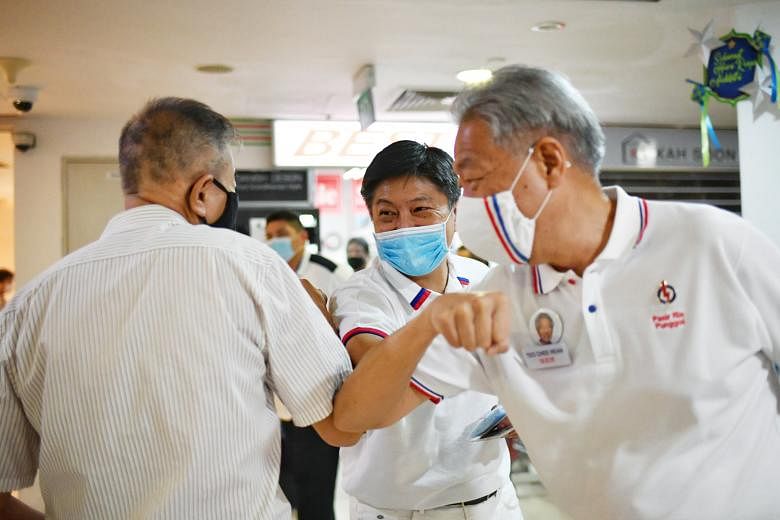 Senior Minister Teo Chee Hean (right) and People's Action Party candidate for Sengkang GRC Ng Chee Meng (centre) exchanging elbow bumps with a resident during a walkabout at Rivervale Plaza yesterday. The PAP team is standing against a team from the 