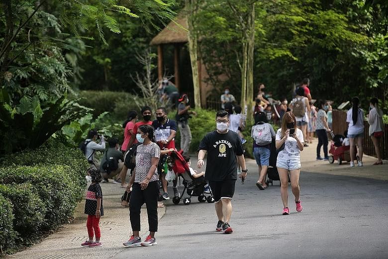 Visitors walking past a thermal scanner and checking in via SafeEntry yesterday before proceeding to the entrance of the Singapore Zoo, where they had their e-tickets scanned. Jurong Bird Park and the River Safari have also reopened, while the Night 