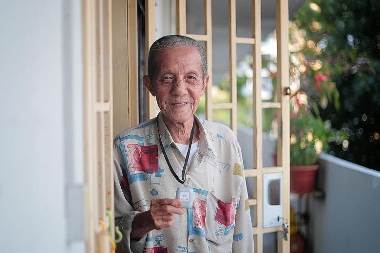 Mr Ng Cheong Hwee, 82, with his TraceTogether token, which he wears around his neck whenever he goes out. Mr Ng does not own a smartphone. He had never heard of TraceTogether either, as he does not keep up with the news. Volunteers and staff with the