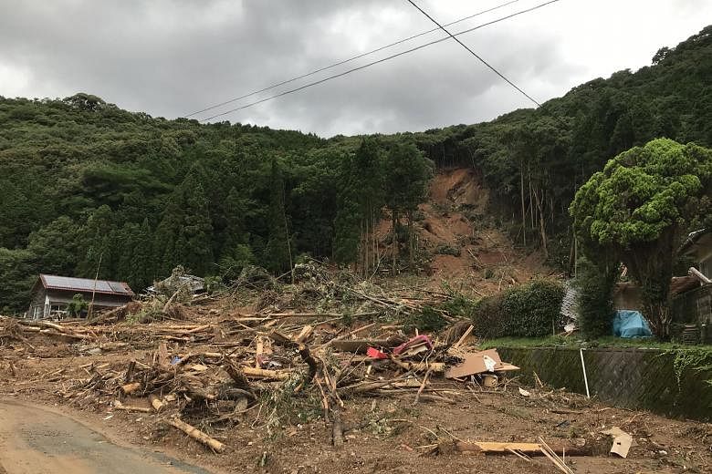 A couple looking around the site of their parents' house damaged by torrential rain in Kuma town yesterday. Heavy rain is expected to continue today.