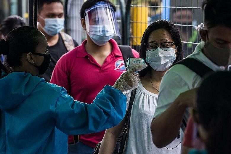 A passenger having her temperature taken before boarding a bus at a station in Manila yesterday. Even after the three-month lockdown was lifted on June 1, the Philippine government was forced to shut down the Metro Rail Transit in Manila, the capital