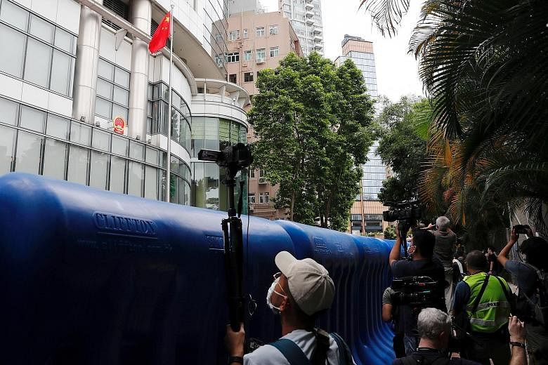 Journalists filming the opening ceremony from behind water barriers. The office is temporarily located at Metropark Hotel in Causeway Bay. (From left) Mr Luo Huining, chief of Beijing's liaison office in Hong Kong, Chief Executive Carrie Lam, former 