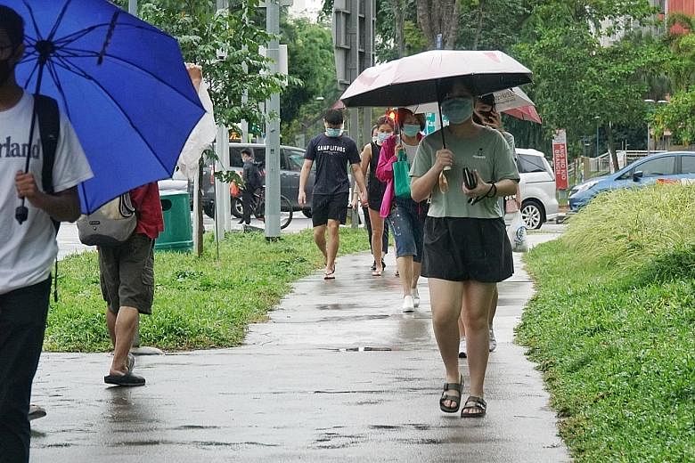 Pedestrians along Ang Mo Kio Avenue 3 at around 6pm yesterday. Temperatures dipped to a low of between 22.9 deg C and 26 deg C. Daily midday temperatures had ranged between 28 deg C and 32 deg C for the past week. ST PHOTO: KHALID BABA
