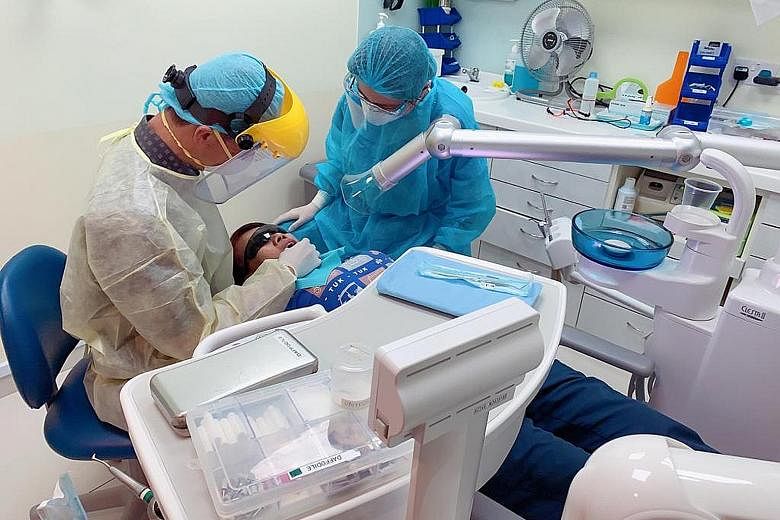 Dr Wong Dai Chong (left) and a nurse treating a patient at the Q&M Dental Centre in City Square Mall yesterday. As part of its precautionary measures, Q&M Dental Group has installed in all treatment rooms a second aerosol suction machine, which is ab