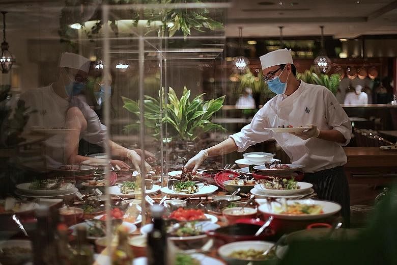 Chef Ryan Tham at a buffet station during lunchtime at Four Seasons Hotel Singapore’s One-Ninety. The acrylic screens let guests view dishes while preventing contamination.