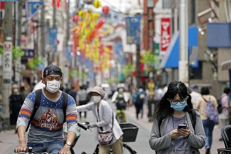People in a shopping street in Tokyo earlier this month. Japan's leaders are hesitant to adopt measures that will further hurt the economy. The country chose to further ease restrictions on Friday.