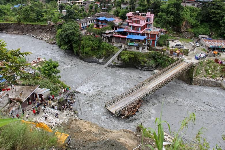 People gathering near a bridge that was damaged by floodwaters at Raghu Ganga River in Myagdi, 200km north-west of the capital Kathmandu, where several houses were destroyed. Landslides and flash floods are common in mountainous Nepal during the June