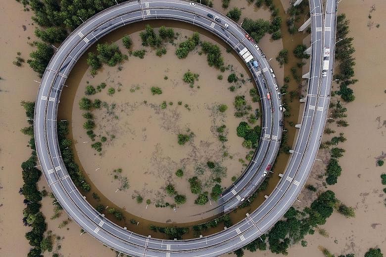 This aerial view shows workers repairing a breached dam in Jiujiang, Jiangxi province, yesterday. Warning levels were breached at over 70 flood-monitoring stations yesterday, according to ministry data. PHOTO: AGENCE FRANCE-PRESSE The aerial view of 