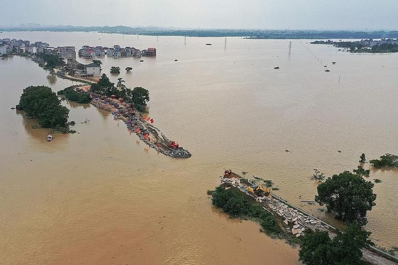 This aerial view shows workers repairing a breached dam in Jiujiang, Jiangxi province, yesterday. Warning levels were breached at over 70 flood-monitoring stations yesterday, according to ministry data. PHOTO: AGENCE FRANCE-PRESSE The aerial view of 