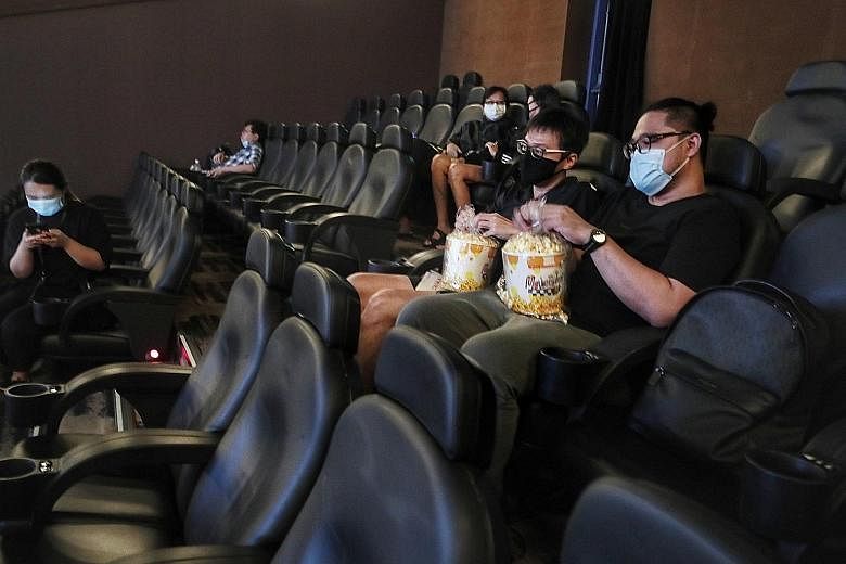 Above: Mr Thomas Chih (left) and his friend, who wanted to be known only as Mr Cortez, 36, having popcorn at the 9.50am screening of biographical drama Escape To Pretoria at Shaw Theatres Nex yesterday. ST PHOTO: KELVIN CHNG Left: (From right) Movieg