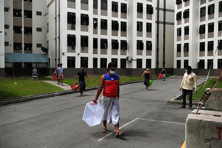 Residents of Tampines Dormitory heading to the food collection centre to pick up their lunch early last month. Many workers staying in dormitories who are infected are likely to show no symptoms, allowing the virus to continue spreading and making th