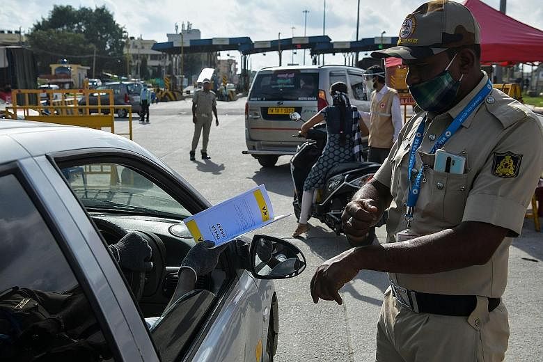 A policeman at the Karnataka-Tamil Nadu state border checkpost on the outskirts of Bangalore directing people in a car from neighbouring Tamil Nadu to undergo health screening on Monday. The Indian city of Bangalore, which saw over 1,300 Covid-19 cas