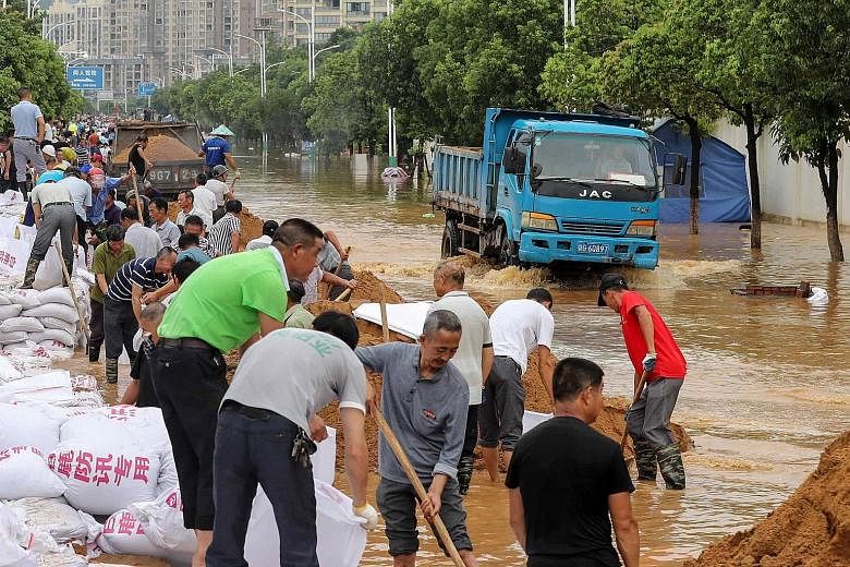 Above: People building anti-flood barriers next to a flooded street in Jiujiang on Monday. 