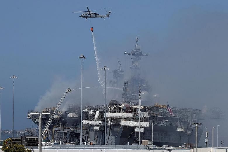 US Navy helicopters and city firefighters fighting the spreading fire on the amphibious assault ship USS Bonhomme Richard at US Naval Base San Diego on Monday. The warship caught fire on Sunday. PHOTO: REUTERS