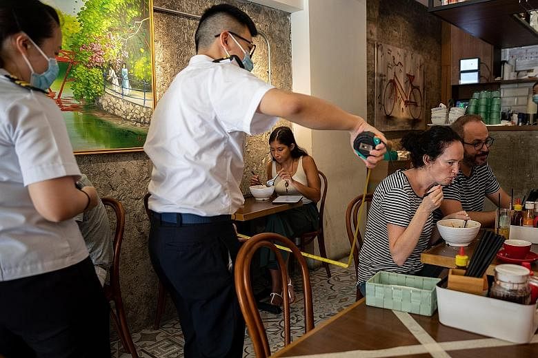 Officers from the Food and Environmental Hygiene Department measuring the distance between tables at an eatery in Hong Kong on Thursday. The city is now one of the first places in the region to see a new wave of Covid-19 cases dwarfing previous ones.
