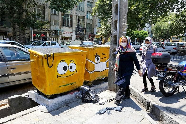 Iranians walking past street bins painted with drawings of sad or masked faces in a campaign to spread awareness of Covid-19, which has infected an estimated 25 million Iranians, with another 35 million at risk. PHOTO: AGENCE FRANCE-PRESSE Gravedigge