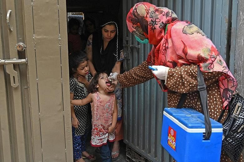 A health worker administering polio vaccine drops to a child during a polio vaccination door-to-door campaign in Lahore, Pakistan, yesterday. The South Asian country yesterday resumed its polio vaccination campaign after a four-month pause due to the