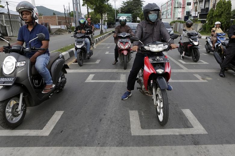 Motorists in Indonesia's Banda Aceh stopping in designated safe distancing spots at a traffic light as part of measures to curb the spread of Covid-19. Indonesia has been easing restrictive measures under a "new normal" but has seen record cases and 