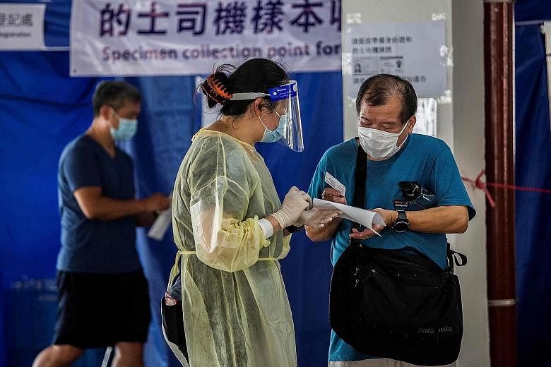 A taxi driver speaking to a health worker before getting tested for the coronavirus at a makeshift testing station in a carpark in Hong Kong on Sunday. The rule making it compulsory for people to wear face masks in indoor public venues will kick in t