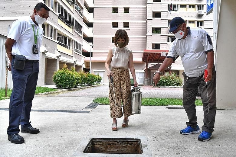 Senior Minister of State for the Environment and Water Resources Amy Khor trying her hand at oiling the drains at Block 408 Bukit Batok West Avenue 4 yesterday. ST PHOTO: CHONG JUN LIANG