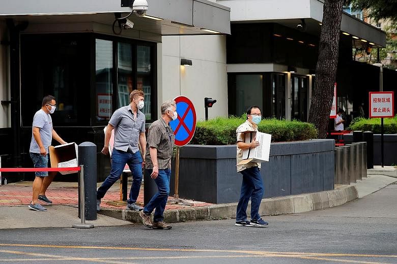 Far left: Police officers detaining a man who tried to display a sign outside the US consulate in Chengdu. Left: People leaving the consulate in Chengdu yesterday. PHOTOS: REUTERS A worker removing a sign at the entrance to the United States consulat