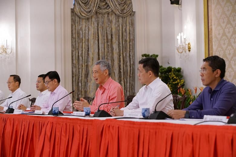 Prime Minister Lee Hsien Loong announcing the new Cabinet line-up at a press conference on Saturday, flanked by Deputy Prime Minister Heng Swee Keat (left) and Trade and Industry Minister Chan Chun Sing, and other current and new office-holders. PHOT