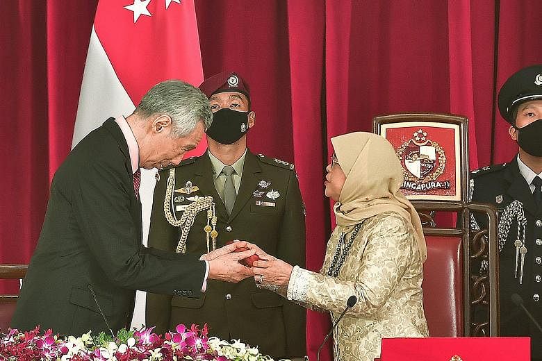 Prime Minister Lee Hsien Loong receiving the instrument of appointment from President Halimah Yacob at the Istana yesterday, during the swearing-in ceremony for the Prime Minister and other Cabinet ministers. ST PHOTO: DESMOND WEE
