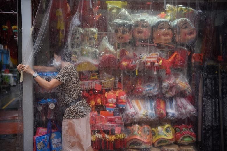 A shopkeeper covering her wares with a plastic sheet at a shop in Chinatown, just before a heavy downpour at around 1pm yesterday. According to Meteorological Service Singapore, thundery showers can be expected till the end of this month, with a dail