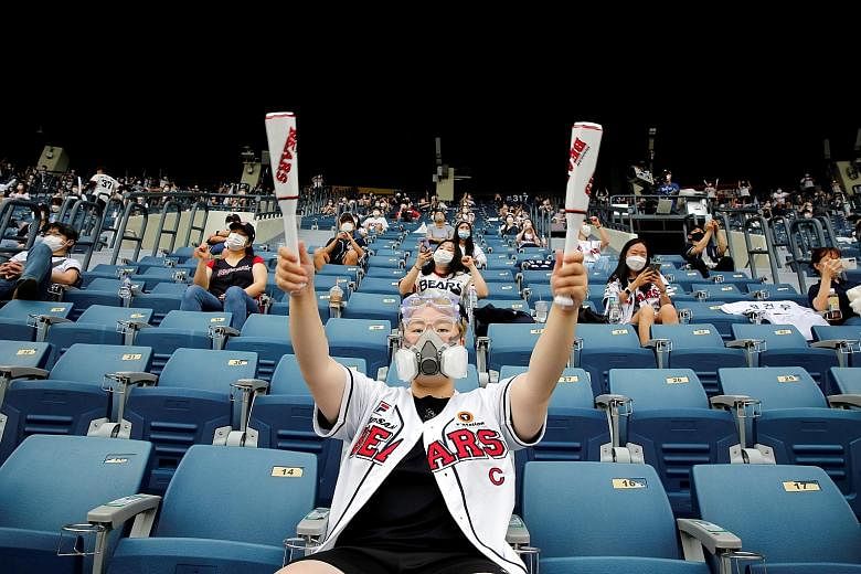 Fans keeping a safe distance from one another during a baseball game at a stadium in Seoul on Sunday. South Korea, which eased Covid-19 curbs in May, has had to reimpose them as a second wave of infections hit some places. People eating in a designat