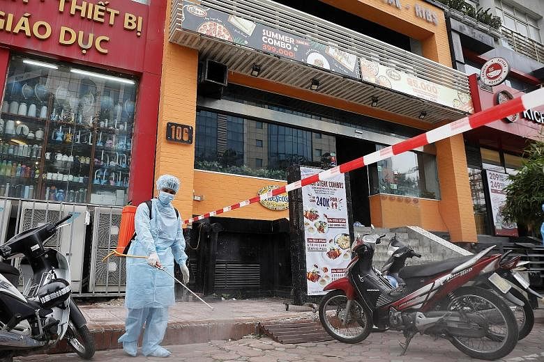 A worker spraying disinfectant outside a pizza parlour in Hanoi where a worker tested positive for Covid-19 after returning from Danang. Apart from the capital, Vietnam's new infections are in Danang, Ho Chi Minh City and Dak Lak province in the cent