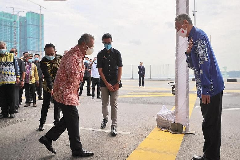 PM Lee and Tan Sri Muhyiddin greeting each other yesterday at the Causeway, where the two leaders witnessed the ceremony to mark the resumption of the Johor Baru-Singapore Rapid Transit System Link. The thick yellow line marks the international bound