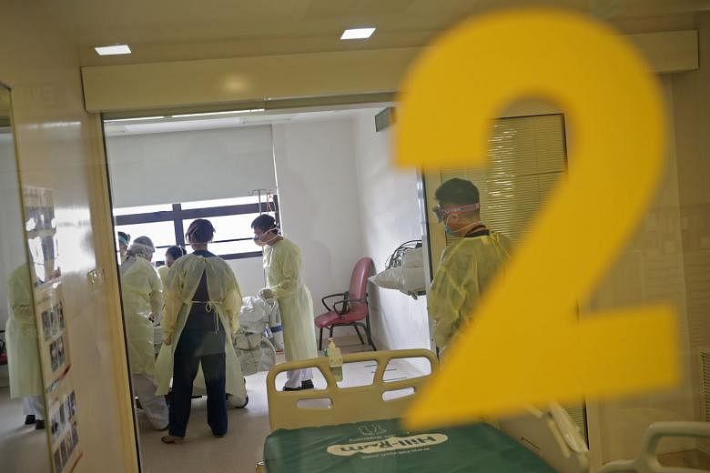 Healthcare workers preparing to transfer a suspected Covid-19 patient at a Singapore General Hospital isolation room. Preparedness is a key factor helping to keep Singapore's ICU admission - and fatality - rates from the disease low, with healthcare 