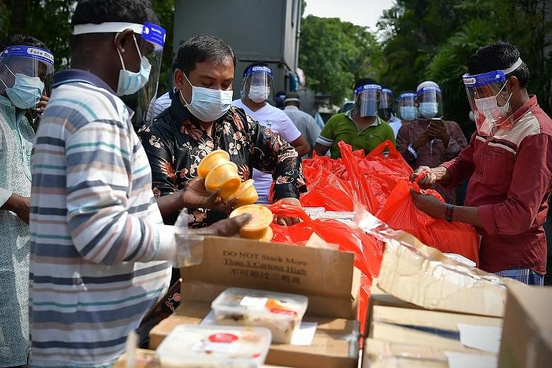 Safety coordinator and supervisor Billal Hossein (second from left) sorting out meals prepared for foreign workers at a factory in Sungei Kadut yesterday. About 6,000 migrant workers staying in 78 factory-converted dormitories enjoyed free meals from