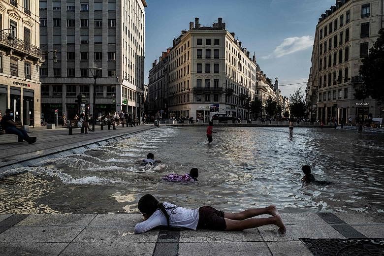 Children cooling off in a fountain in Lyon on Thursday amid a heatwave in France. An increase in Covid-19 cases also prompted French officials to tighten face mask requirements in several cities, with many making them mandatory outdoors as well as in