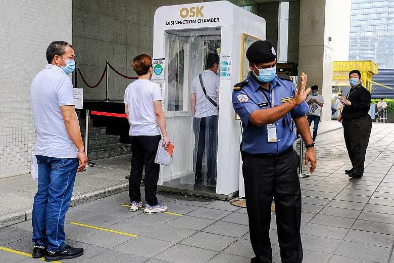 People wearing masks and maintaining social distancing while waiting in line to enter a disinfection chamber at Plaza OSK in Kuala Lumpur. PHOTO: BLOOMBERG