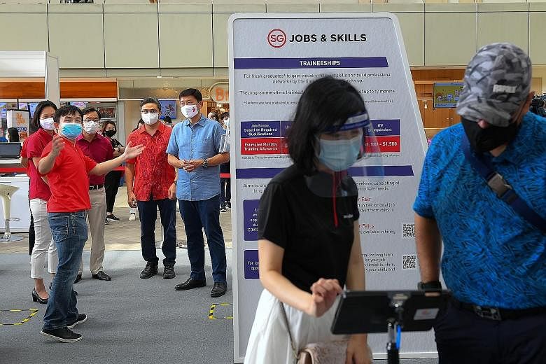 Senior Minister of State for Foreign Affairs and Transport Chee Hong Tat (in light blue top) being briefed by Mr Toh Swee Chien (in red polo T-shirt) of SkillsFuture Singapore at a job fair at HDB Hub in Toa Payoh yesterday, along with (from left) MP
