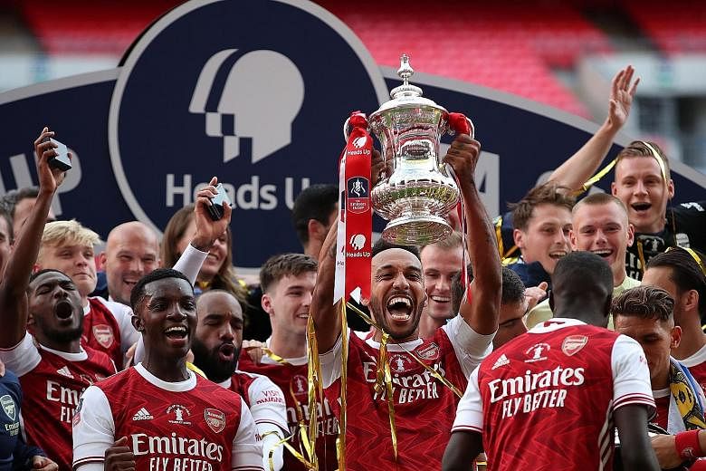 Above: Pierre-Emerick Aubameyang beats Chelsea goalkeeper Willy Caballero to give Arsenal a 2-1 lead at Wembley Stadium, which they held on to win. Left: Gabonese striker and captain Aubameyang holding the trophy as the Gunners celebrate their record