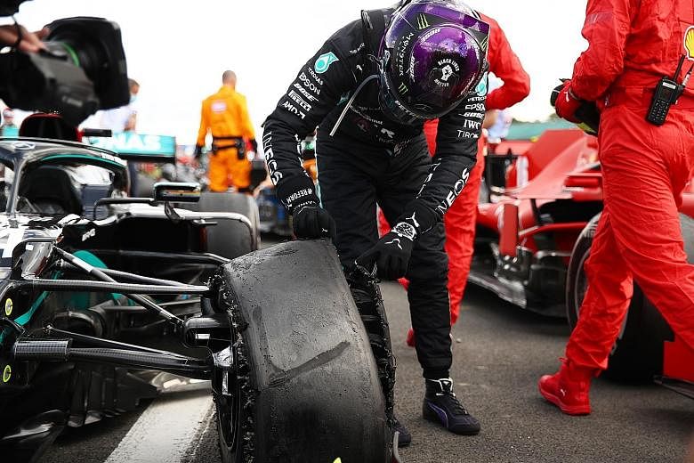 Lewis Hamilton checking his Mercedes car's front left tyre after hanging on to win the British Grand Prix for a seventh time at Silverstone yesterday despite a puncture on the final lap.