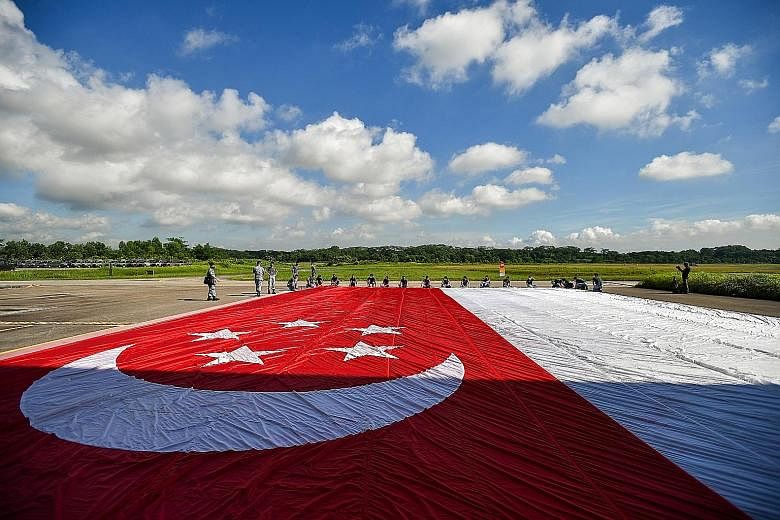 The state flags prepared for this year's National Day Parade fly-past must be carefully rolled up before they can be rigged onto the Chinook helicopters that will fly them across Singapore at a height of about 305m. Among those involved in the state 
