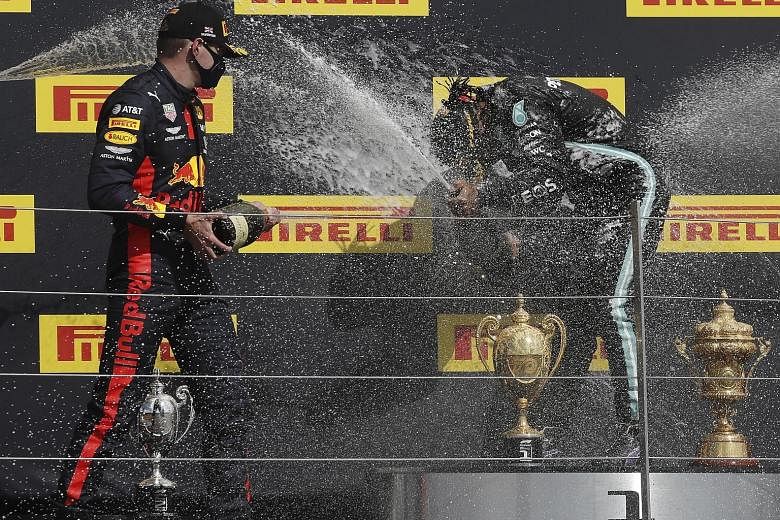 Race winner Lewis Hamilton (above) inspecting the punctured tyre on his Mercedes before celebrating on the British Grand Prix podium with runner-up Max Verstappen.