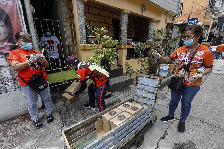 City workers leaving food supplies on the doorstep of a house in a village under quarantine in Caloocan city, Metro Manila, yesterday. The Philippine Health Ministry yesterday reported 3,226 new cases and 46 deaths, bringing total infections to 106,3