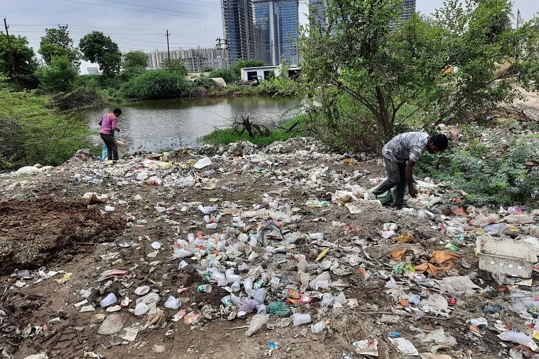 Mr Mainal Ali (right) at work collecting recyclable items from among waste in Noida, a suburb near Delhi. Waste pickers work without gloves or protective equipment, leaving them exposed to health risks.