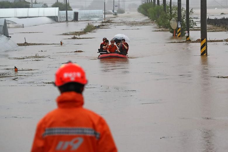 Big waves battering Shengsi county in eastern China's Zhejiang province yesterday as Hagupit, the fourth typhoon this year, struck. PHOTO: XINHUA Rescue workers in South Korea helping people cross a flooded field in a village near Cheonan on Monday. 