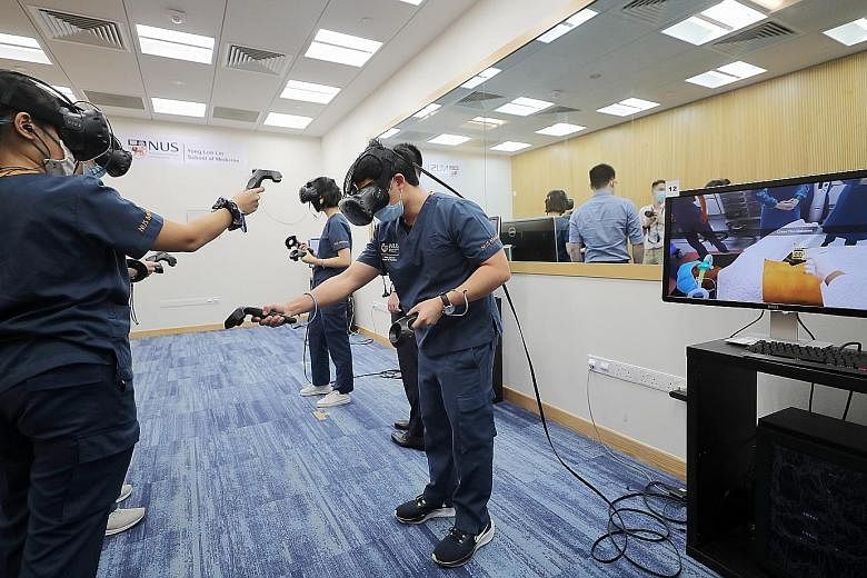 A group of third-year students at the NUS Yong Loo Lin School of Medicine learning in a virtual environment with the use of VR headsets and hand-held controllers. Their movements are observed by educators who guide them.