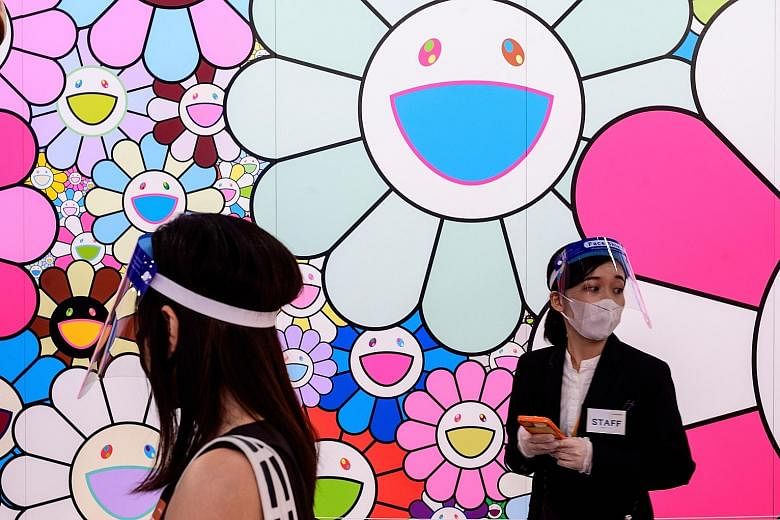 People wearing face shields next to Pop Up Flower, a work by artist Takashi Murakami, at a media preview of Stars: Six Contemporary Artists From Japan To The World at the Mori Art Museum in Tokyo last month.